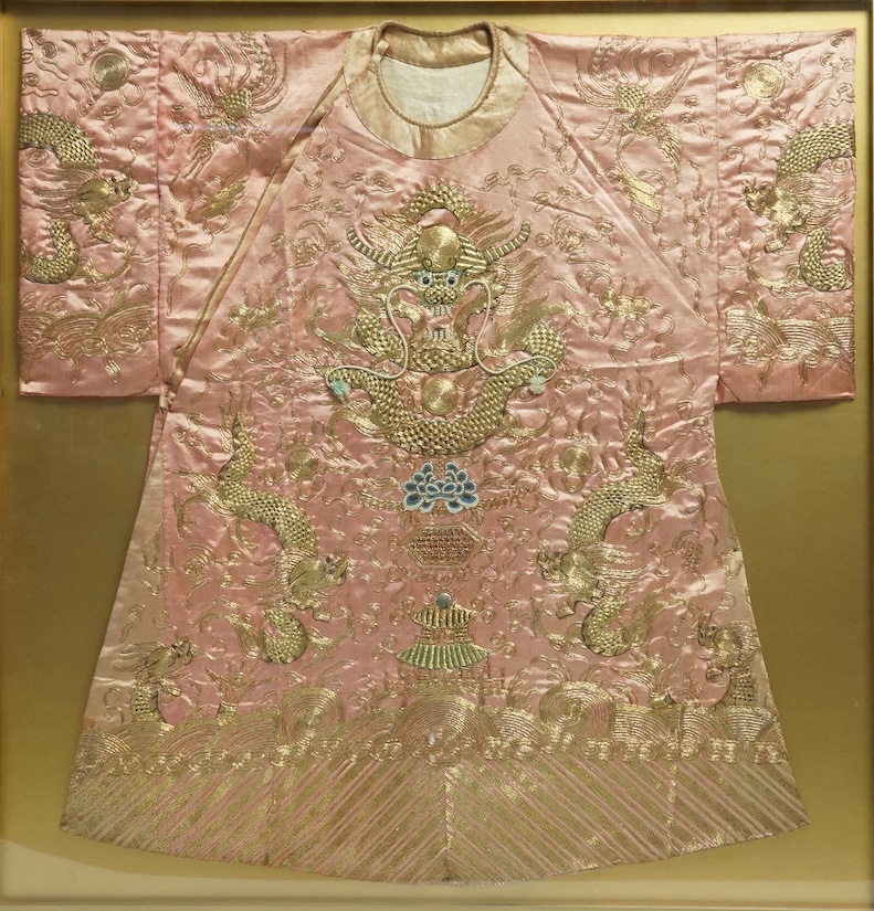 A framed late 19th early 20th century Chinese pink silk and gold embroidered dragon jacket. The dragons embroidered with raised couched gold thread work, surrounded by Phoenix and auspicious symbols. Jacket 69cm wide x 7